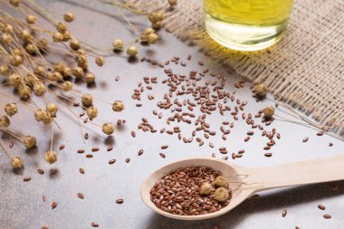 Ahşap kaşıkta keten tohumu ve grunge yüzeyde keten tohumu yağı, bez çuval bezi, yakın çekim.