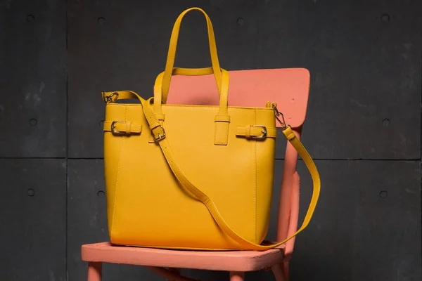 Pembe sandalyede sarı moda çantası, alışveriş konsepti, grunge arkaplan