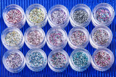 mavi arkaplandaki çiviler için çok renkli parıltılı akrilik kavanozlar, seçici odaklanma