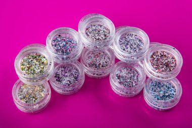 Pembe arka planda tırnakları için çok renkli kıvılcımları olan akrilik kavanozlar, seçici odaklanma