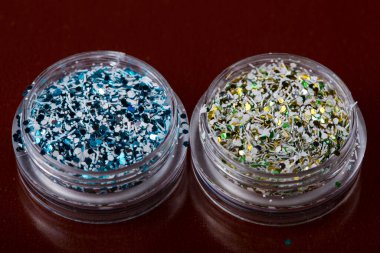 Akrilik kavanozlar, koyu kırmızı arka plandaki çiviler için çok renkli ışıltılar, seçici odaklanma