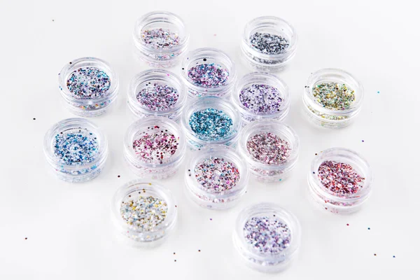 Akrilik kavanozlar beyaz arka planda tırnaklar için çok renkli simler, seçici odaklanma