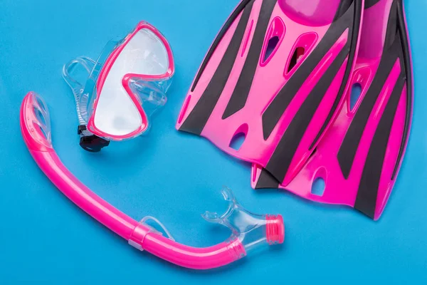 Pembe dalış takımı, maske, şnorkel ve paletler mavi arka planda, tatil ve seyahat konsepti