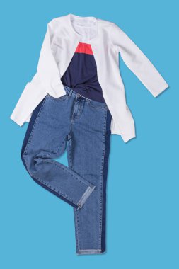 Mavi kot pantolon ve beyaz ceket, mavi arka planda serilmiş, alışveriş konsepti, düz yatış
