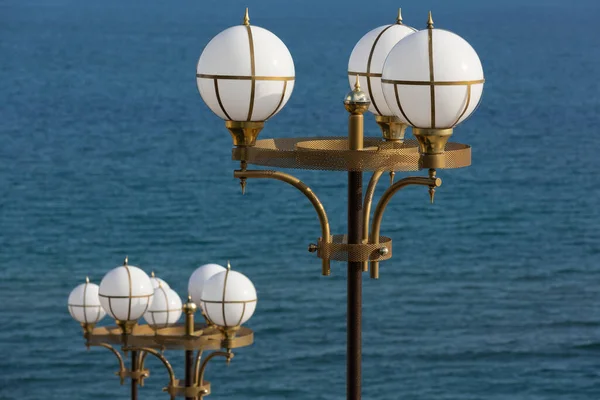 Denizin Arka Planında Yuvarlak Işıkları Olan Iki Sokak Lambası — Stok fotoğraf