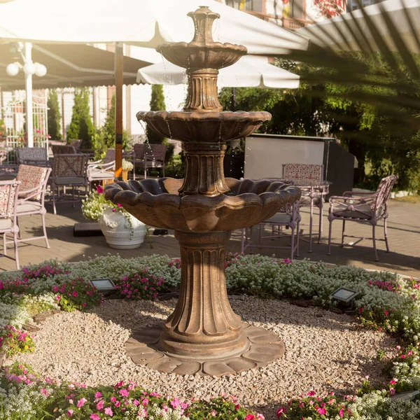 Sokak restoranının yanındaki güzel çeşme, masalar ve çiçekler, güneş ışığı, yaz konsepti ve seyahatte yiyecek.