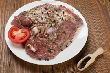 Dilimlenmiş domatesin yanında, beyaz bir tabakta baharatlı hindi eti, dağınık biberlerle çevrili.