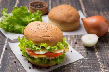 Ön planda hazır burger, eski tahtalarda birkaç çörek ve baharat, köy tarzı.