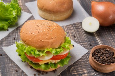 Ön planda hazır burger, eski tahtalarda birkaç çörek ve baharat, köy tarzı.