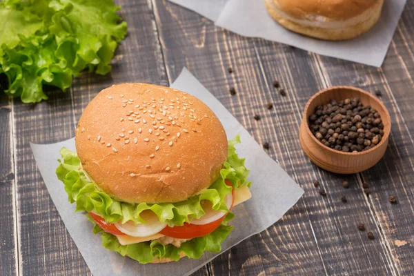 Ön planda hazır burger, eski tahtalarda birkaç çörek ve baharat, köy tarzı.