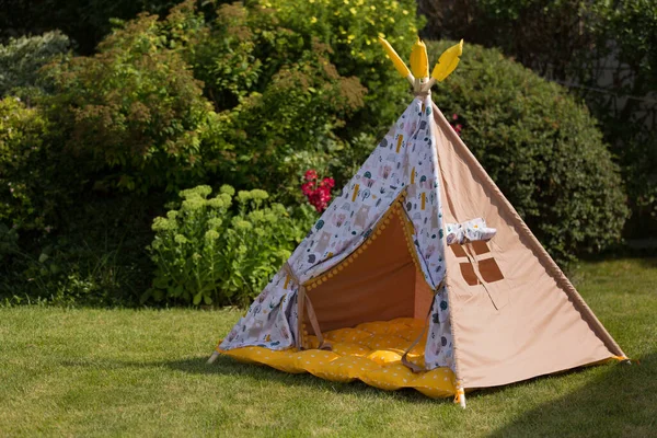 children's tepee tent on a green lawn, outdoor recreation, copy space