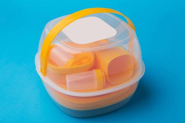 Konteynırda bir dizi plastik tabak, sarı yeniden kullanılabilir tabak, mavi arka planda bir set istiflenmiş.