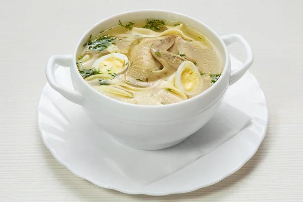 quail soup with noodles and quail eggs in a white plate on the table