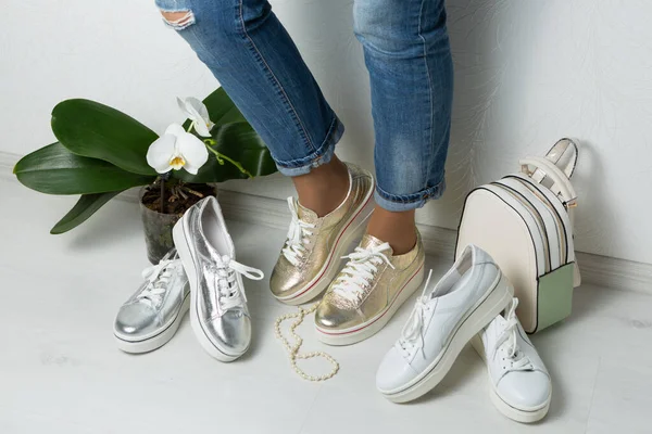 Altın ayakkabılı kadın bacakları, çeşitli kadın ayakkabıları ve aksesuarlarıyla çevrili, alışveriş konsepti