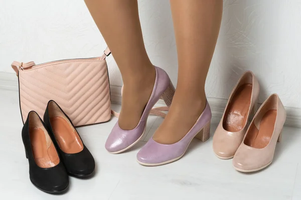 Frauenbeine Fliederfarbenen Schuhen Neben Zwei Paar Schuhen Und Einer Damentasche — Stockfoto