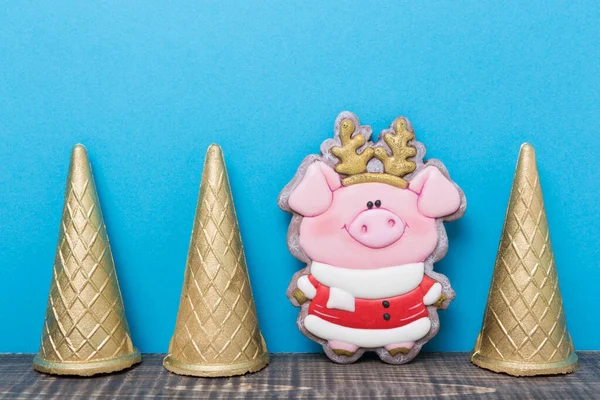 on a wooden board three ice cream cones and a gingerbread cook in the shape of a piglet, on a blue background, a minimal concept