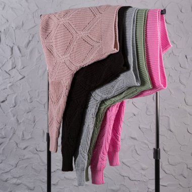 Birçok renkli yün kazak satış tezgahına asılıdır, tavan arası duvarının arka planına karşı, konsept