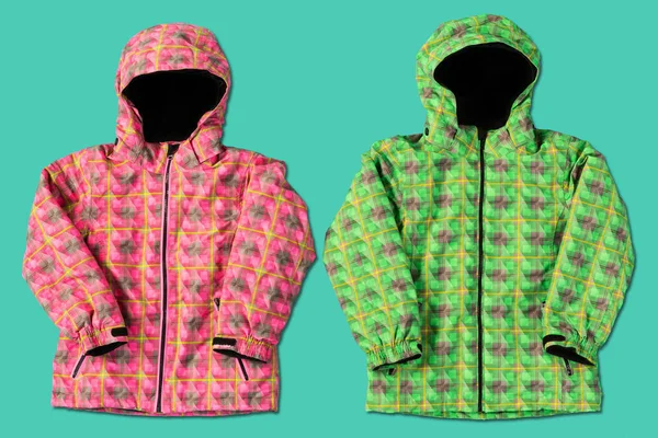 two ski jackets, green and pink, on a turquoise background, concept