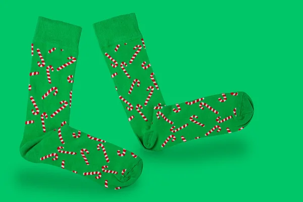 pair of green socks with christmas pattern, laid out as if walking, on green background, concept, copy space