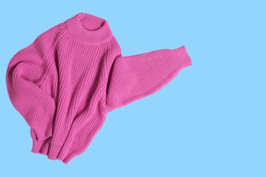 Pink knitted sweater, sleeves to the side, as if indicating an advertisement, concept, on a blue background, copy space