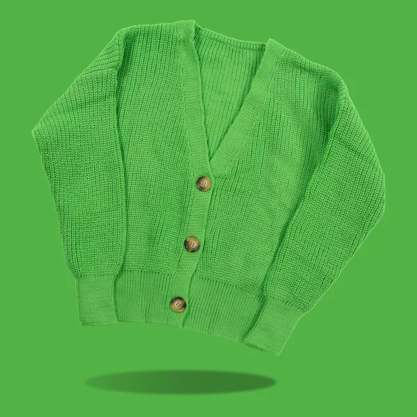 Green knitted women\'s jacket, buttons fastened, levitates, concept, on a green background, casts a shadow