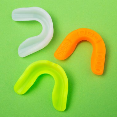 three colored boxing mouth guards lie on a green background, concept, flat lay