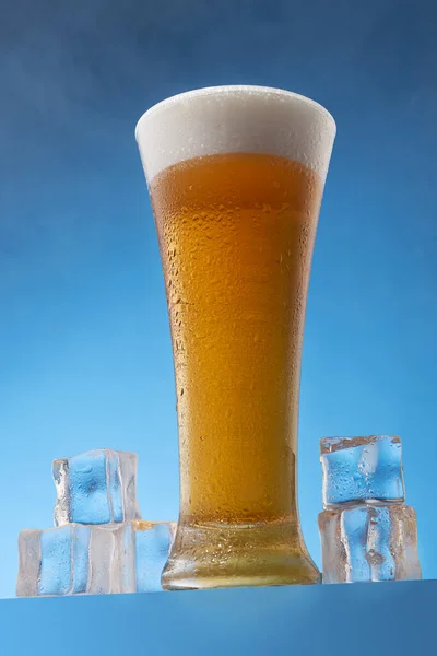 Wysokie Szkło Wypełnione Zimnym Piwem Pianką Otoczone Kostkami Lodu Niebieskim — Zdjęcie stockowe