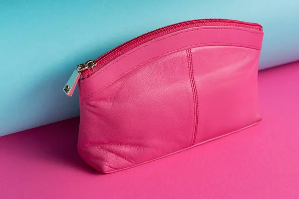 Pink women\'s clutch or wallet is located on a colored background, diagonal arrangement, close-up