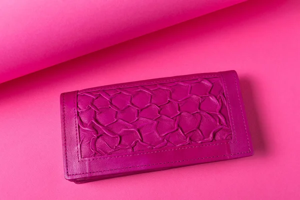 Lilac women\'s leather wallet with a textured finish, located on a pink background, flat lay