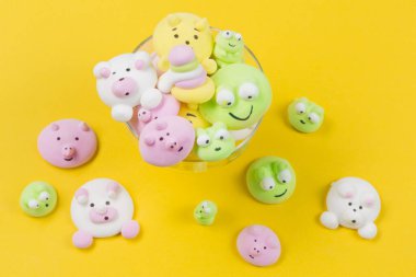 Cam bir fouger içinde çok renkli marşmelovlar ve sarı arka planda boşluklar.