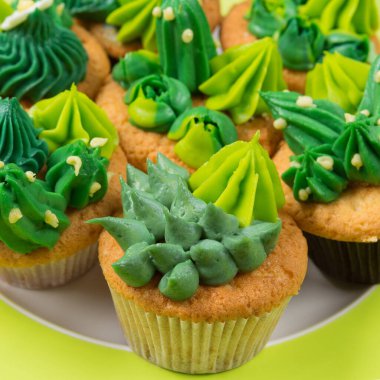 Kaktüs şeklinde kremalı ve yeşil arka planda, bir tabakta sulu kekler.