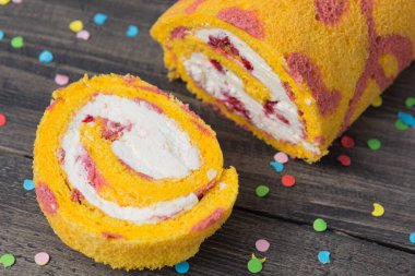 Sarı bisküviler ahşap tahtalarda pembe desenli, renkli süsler, bir parça kesilmiş, ahududu ile dolu yumuşak peynir, doğum günü için atıştırmalık