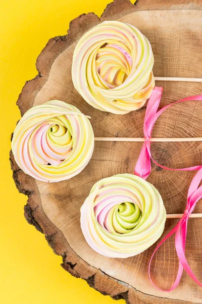 Three Colored Meringues Stick Pink Ribbons Lie Wooden Stand Yellow — Stock Photo, Image