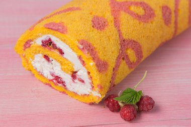 Beyaz kremalı ve ahududulu sarı yuvarlak, pembe tahta tahtalarda, seçici odaklı.