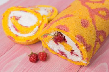 Pembe tahta tahtalarda, bir bisküvi rulosu ve ahududu ile çevrili iki kesik parça, seçici odak