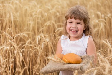 mutlu çocuk buğday tarlasında, kız elinde ekmek tutuyor ve gülüyor, konsept, yaşam tarzı ve hasat, kopyalama alanı