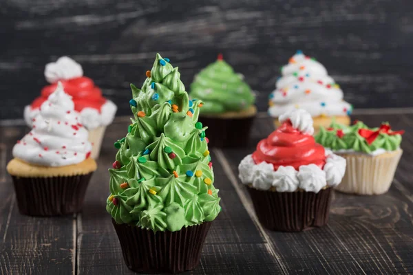 a lot of christmas cupcakes on wooden boards, in the foreground a cupcake in the shape of a christmas tree, christmas