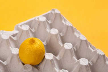 yumurta tepsisinde bir limon, sarı bir arka plan, vitaminler ve tazelik kavramı yoktur