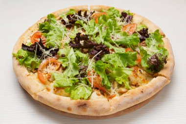 Beyaz ahşap bir masa üzerinde ıspanaklı ve marullu İtalyan pizzası.