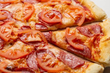 Salamlı ve domatesli İtalyan pizzası, pizza dilimi, yakın çekim.