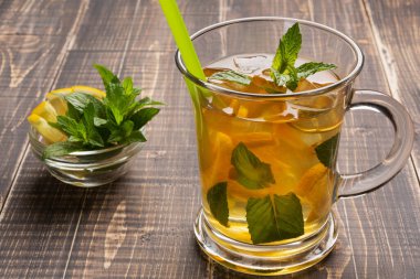 Limonlu, buzlu ve naneli bir bardak çayla ahşap tahtalarda soğuk bir içecek.
