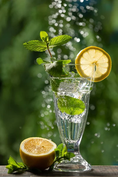 Air Berkilau Gelas Tinggi Batu Mint Dan Sepotong Lemon Sebelahnya — Stok Foto