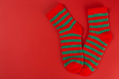 İki yeşil çizgili Noel çorapları, sanki ayak parmaklarının üzerinde, kırmızı arka planda, konsept, düz yatıyordu.