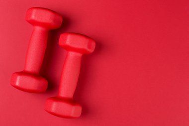 Kırmızı arkaplanda bir çift dambıl var, konsept, boşluğu kopyala