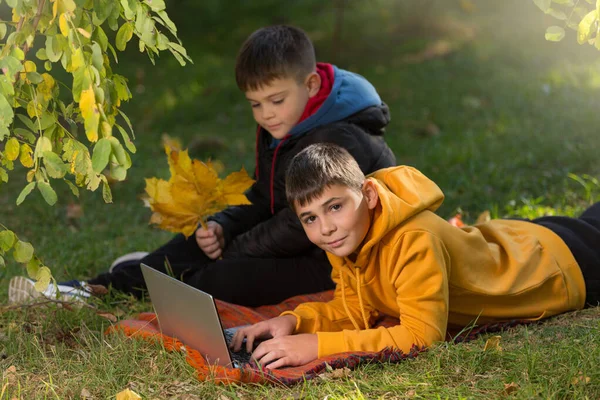 Két Fiú Barát Vagy Testvér Őszi Parkban Egy Laptoppal Lábtörlőn — Stock Fotó