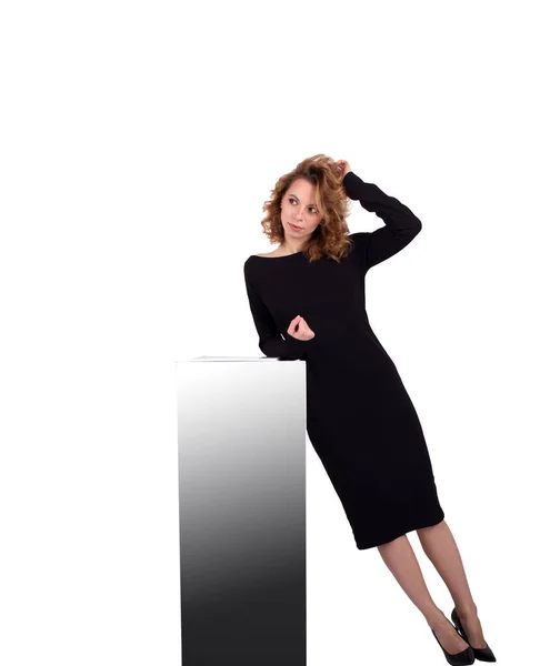 Beyaz arka plandaki dolabın yanındaki siyah elbiseli çekici beyaz iş kadını.