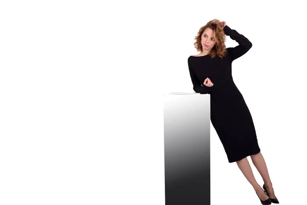 Beyaz arka plandaki dolabın yanındaki siyah elbiseli çekici beyaz iş kadını.