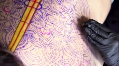 Dövme sanatçısı pembe makineyle siyah dövme yapıyor.