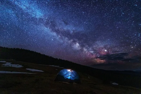 明亮的星空 以高山为背景 银河般的道路 还有红色帐篷的远足者 图库照片