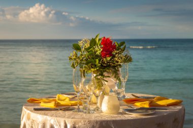 Romantic dinner: table for two and Beach with bouquet Montego Bay - Jamaica clipart